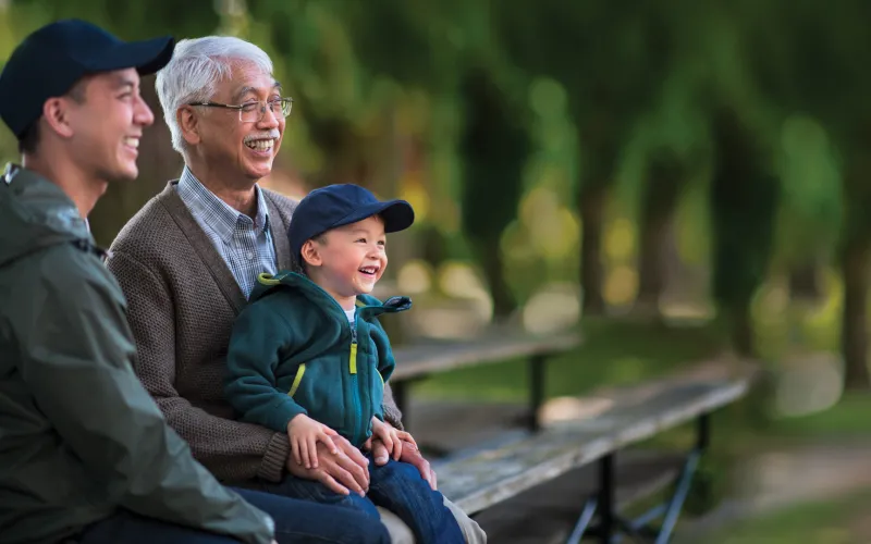 Grandfather with his son and grandchild sitting on a bench