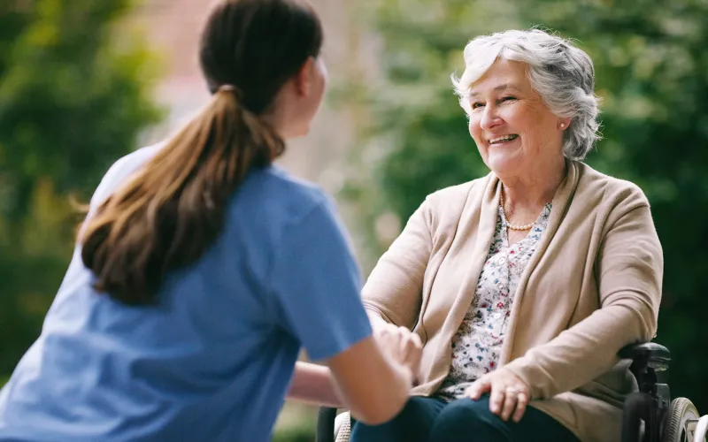 Caretaker helping older woman in wheelchair 