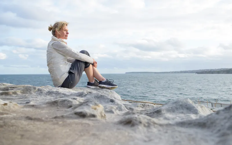 Woman sitting by the ocean