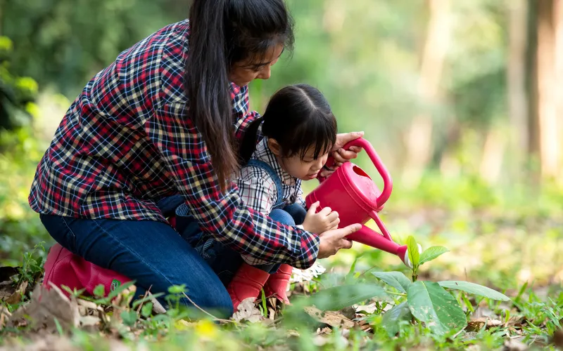 Mother and child watering plant
