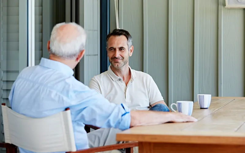 Older father and son talking drinking coffee