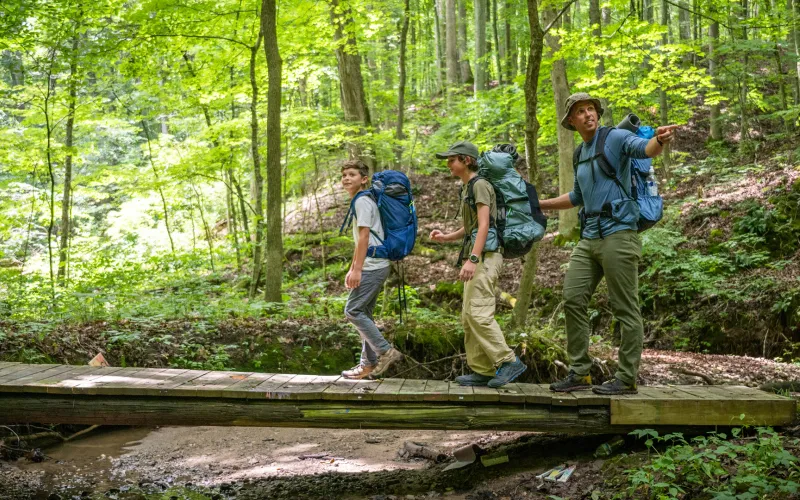 Father with his 2 sons walking over a stream.