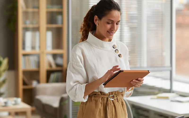 A woman looking at her tablet in an office.