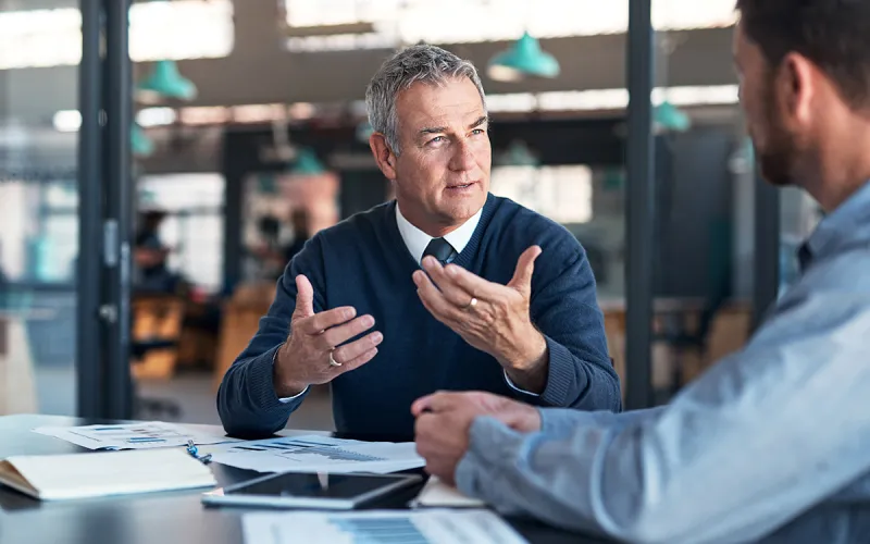 Two men speaking to eachother in an office. 