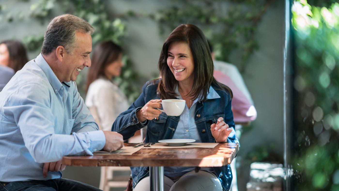 Couple having coffee and laughing at an outdoor cafe 