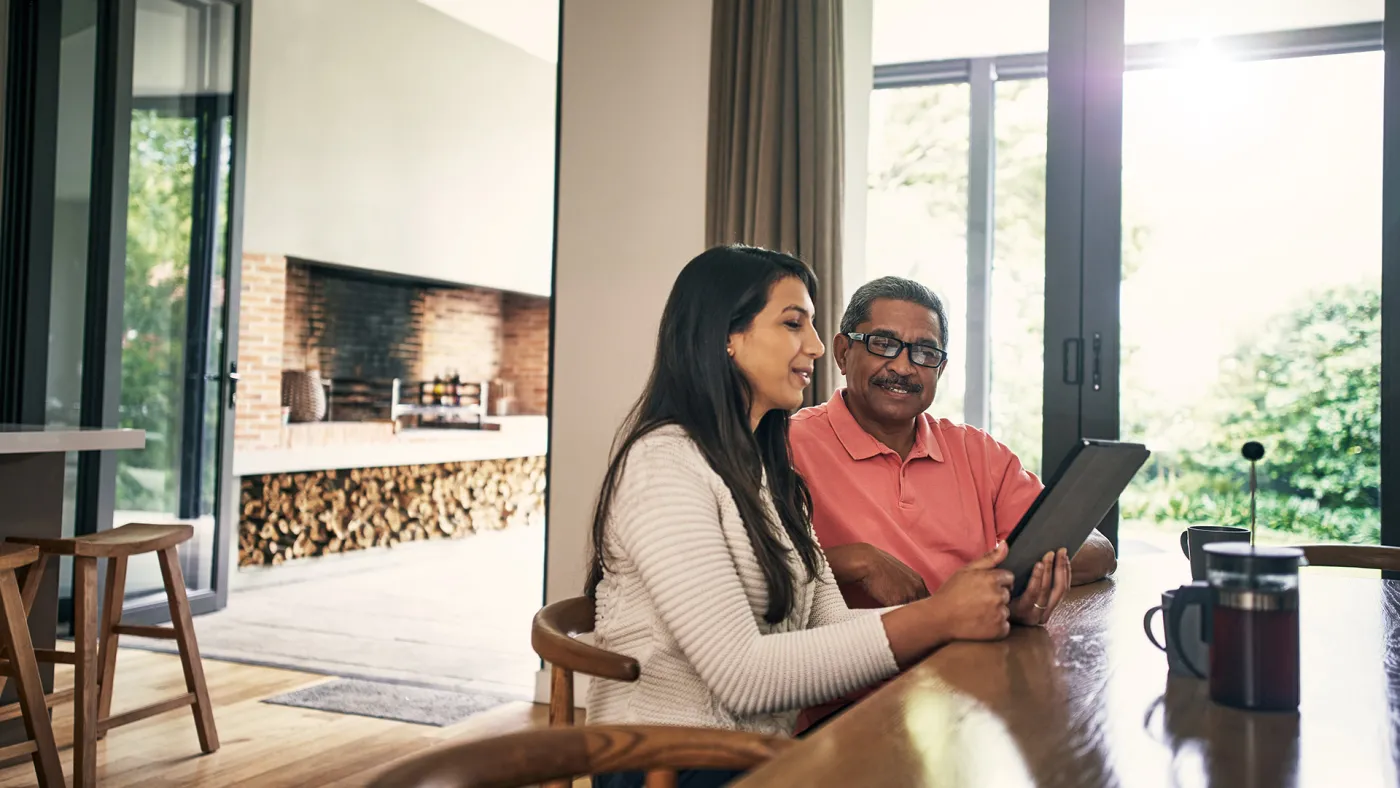Daughter working on finances with father using a tablet