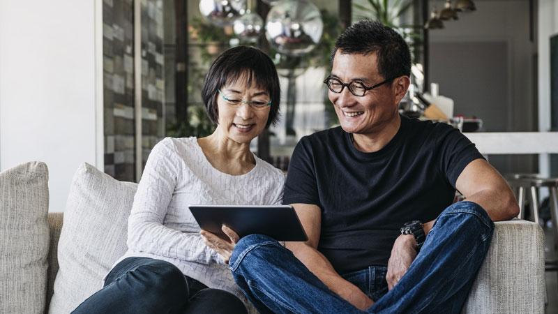 Couple watching a webinar on their tablet while sitting on the couch