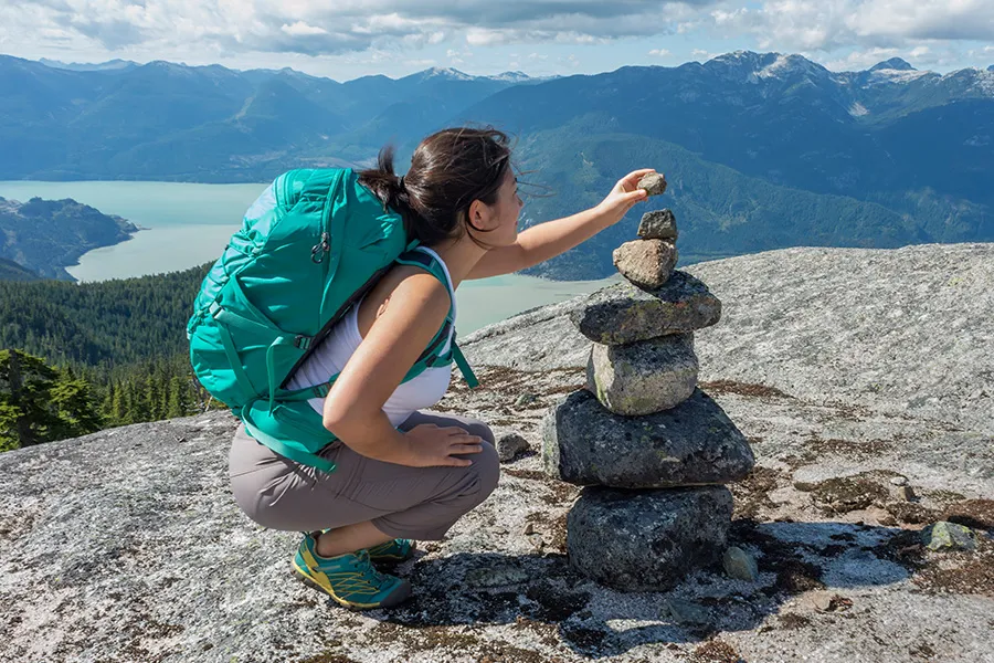 A woman stacking rocks while on a hike in British Columbia. 
