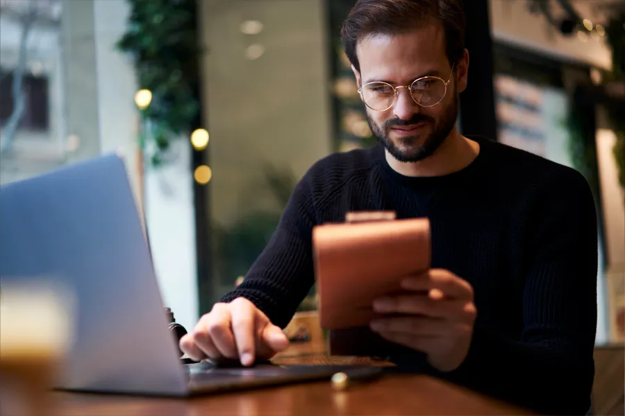 A man reviewing his notepad while working on his computer