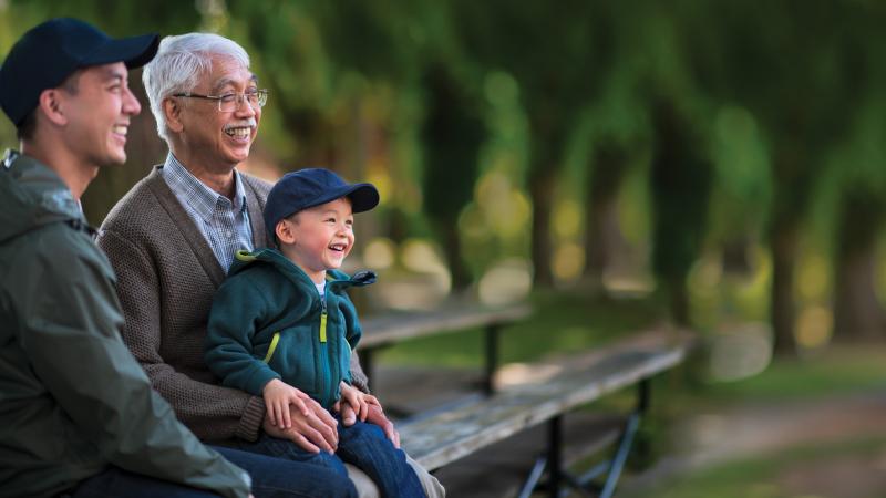 Grandfather with his son and grandchild sitting on a bench