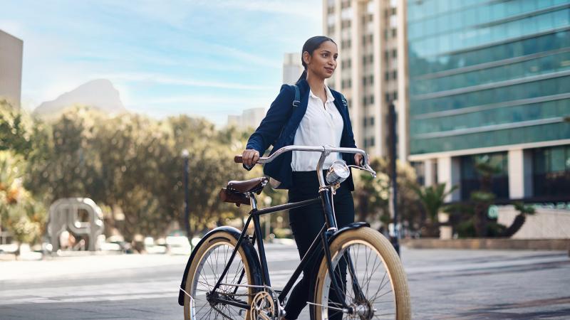 Woman walking with a bike through a city.