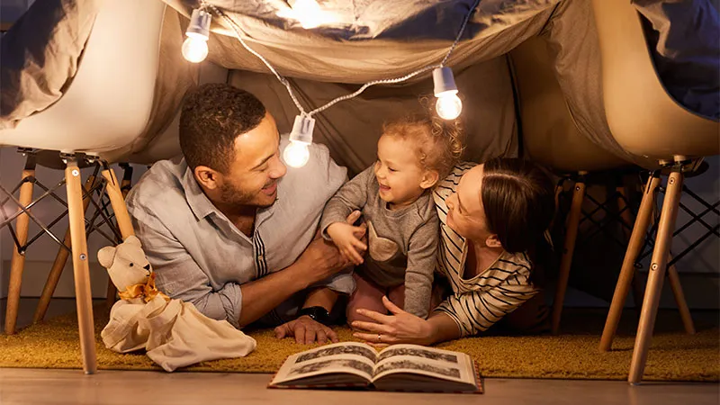 Mother, father and child reading a book at home
